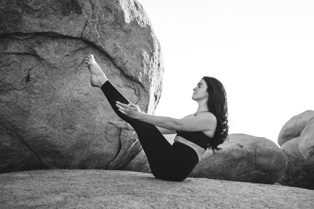 our-services-03 grayscale-photo-of-woman-exercising-on-top-of-large-rock-b-kjou5oyyg